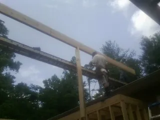 Carpenter setting a ridge beam over a new addition frame — Ice Dam Removal by Roofing Brothers in Sunapee