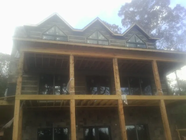 Dormers and porch framing on a large log home under construction — Roof Coating work by our crew in Sunapee