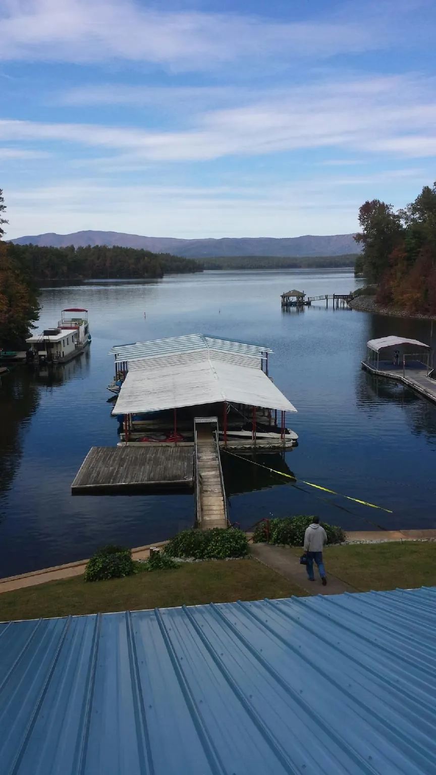 View across a lake from a newly installed blue metal roof in Sunapee