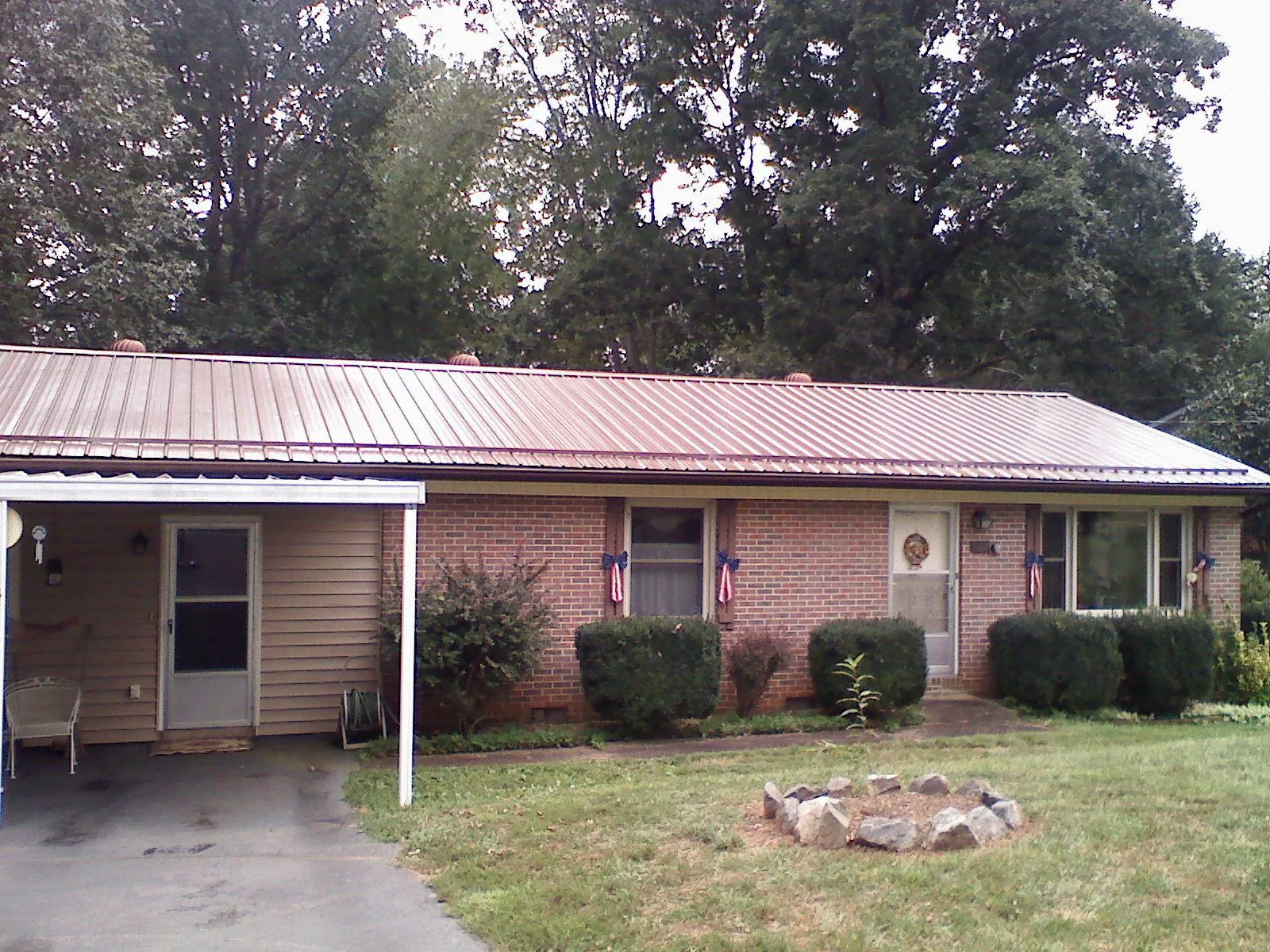 Bronze metal roof and carport on a brick ranch home — Roof Repair work by our crew in Sunapee